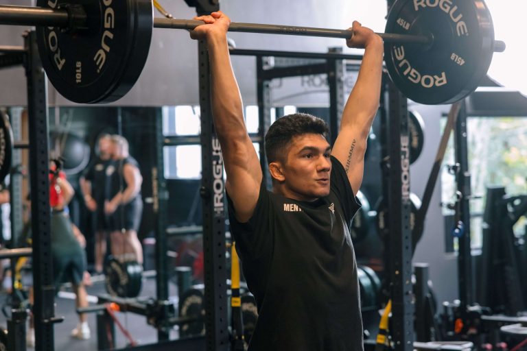 Meathead mover lifting a barbell overhead in the gym
