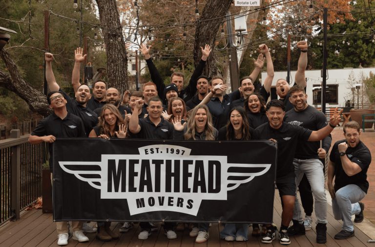 Meathead Movers team cheering behind a company banner