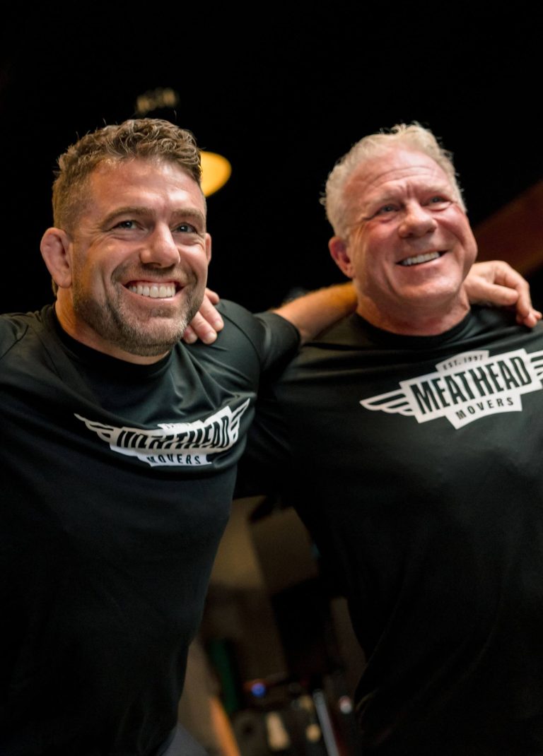 Two smiling Meathead Movers team members embracing