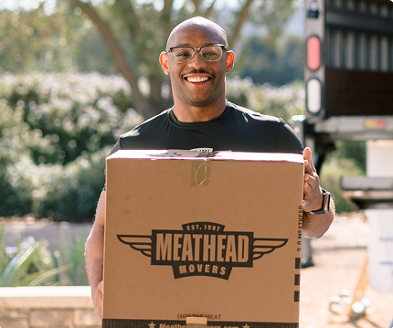 Smiling Meathead mover carrying a branded moving box