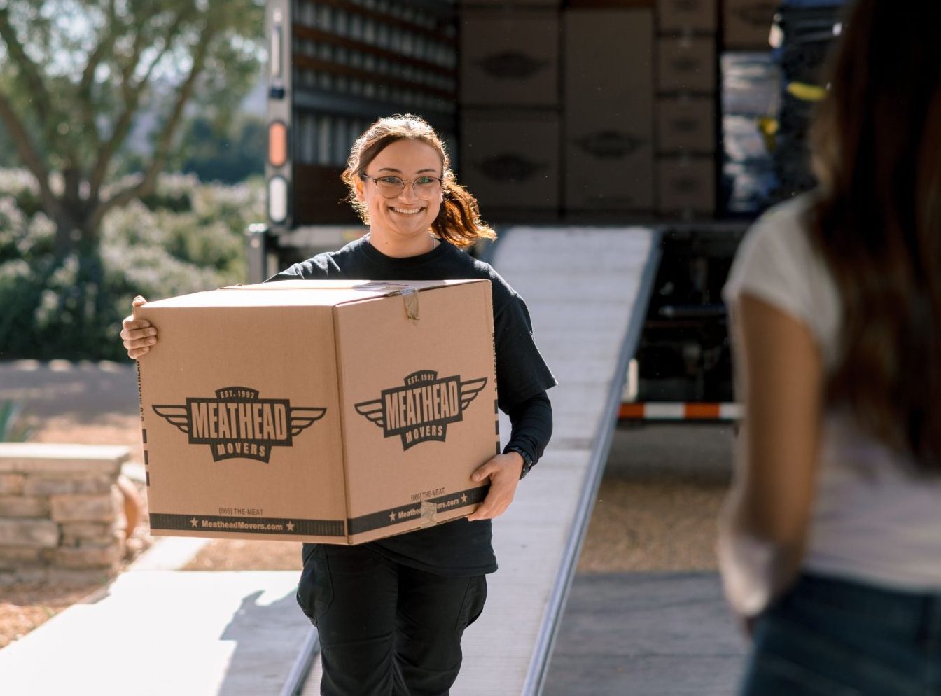 Meathead mover carrying a moving box down a truck ramp