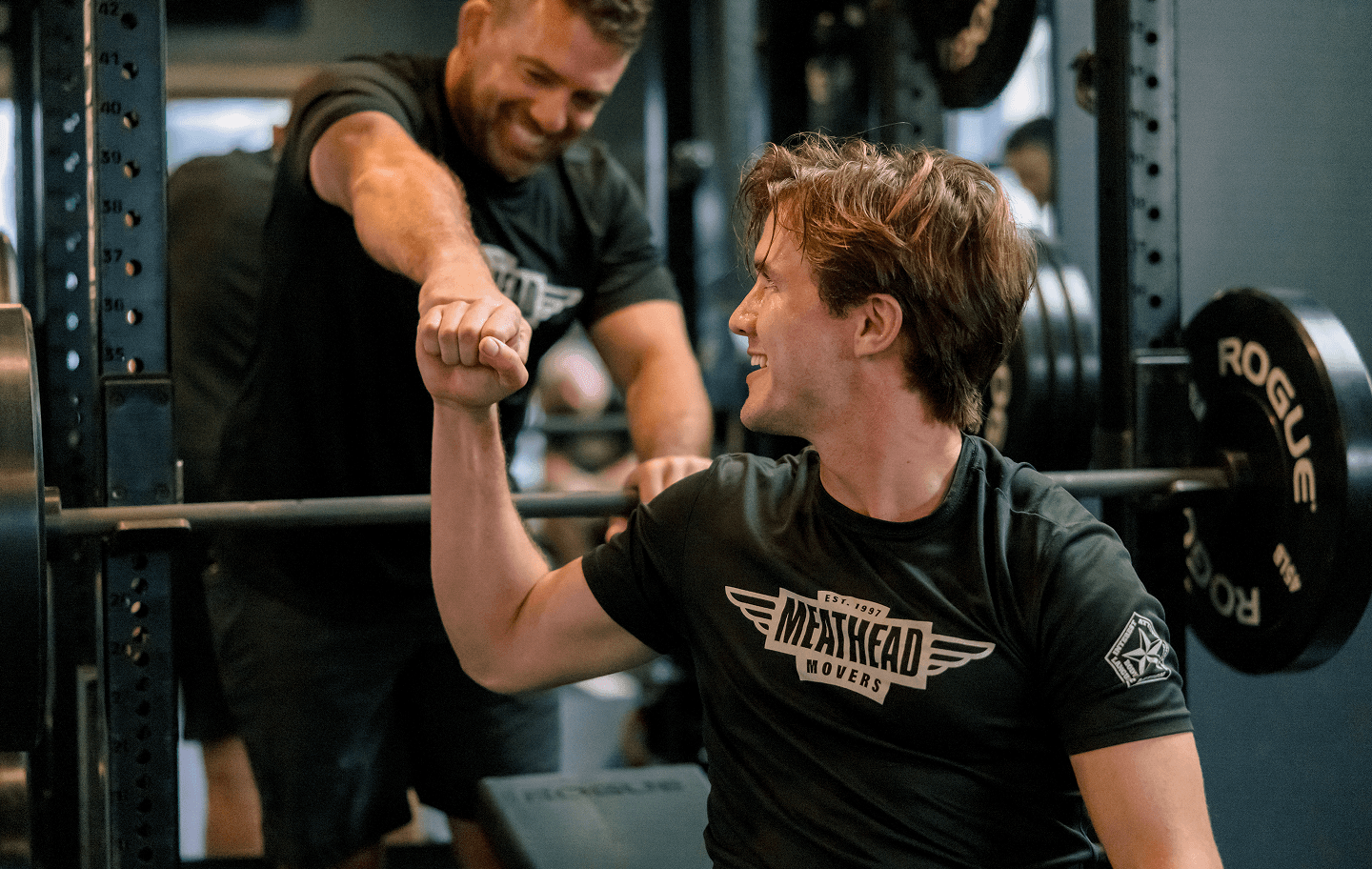 Meathead movers sharing a fist bump during a gym workout