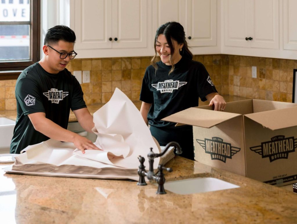 Meathead movers wrapping kitchen items in packing paper