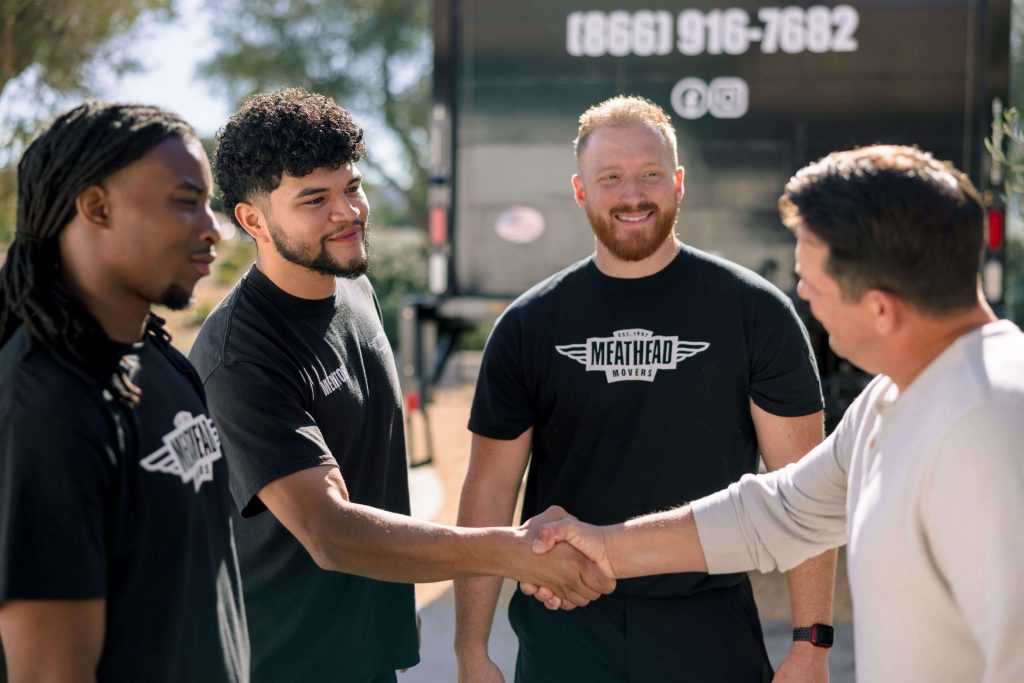Meathead mover shaking hands with a customer next to a moving truck