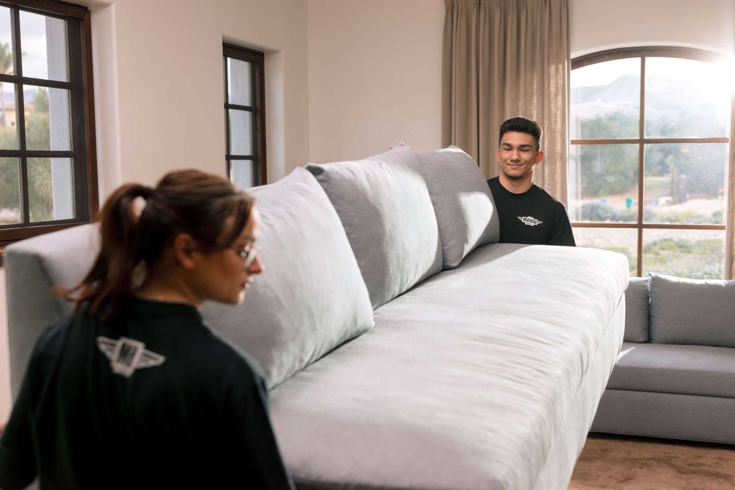 Meathead movers preparing to move a sofa in a bright living room