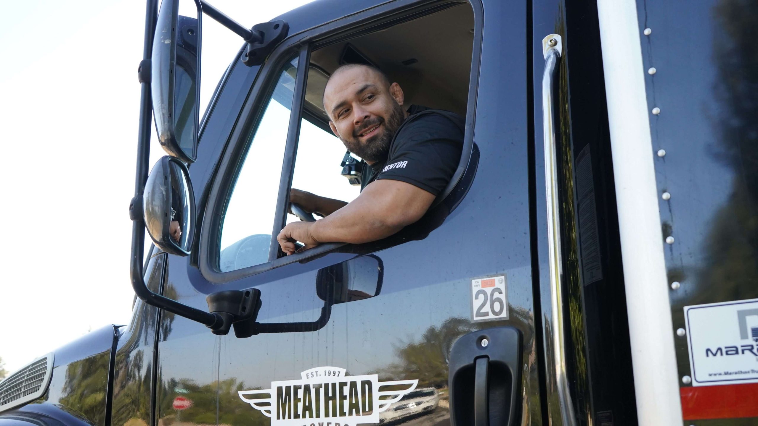 Meathead mover smiling from the driver's seat of a moving truck