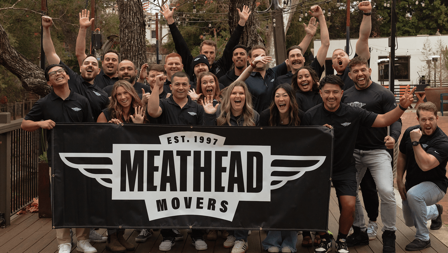 Meathead Movers team cheering behind a company banner