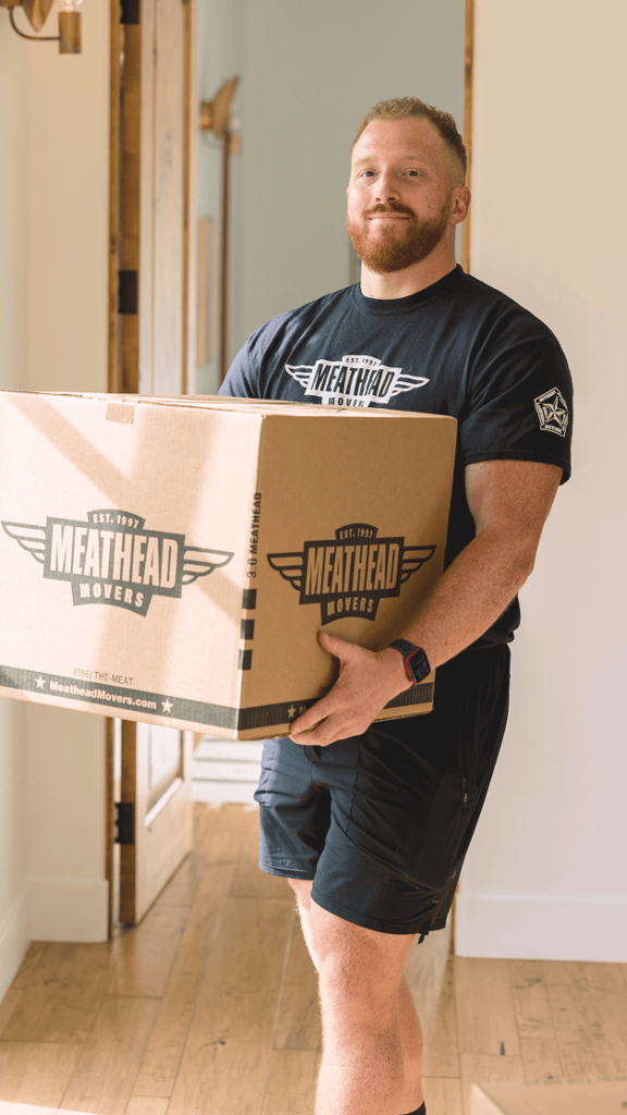 Meathead mover carrying a branded moving box through a home