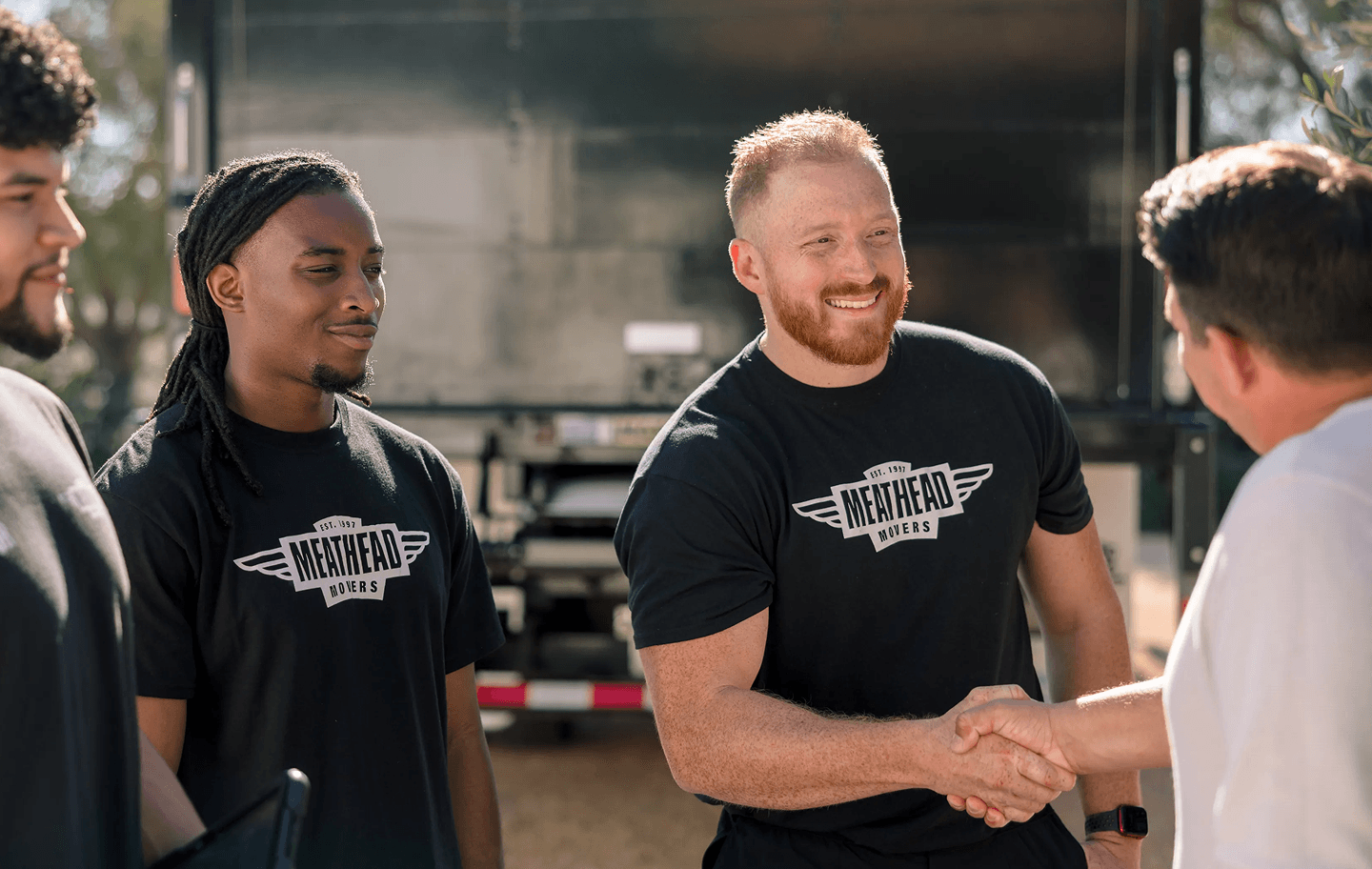 Meathead mover shaking hands with a customer beside a moving truck