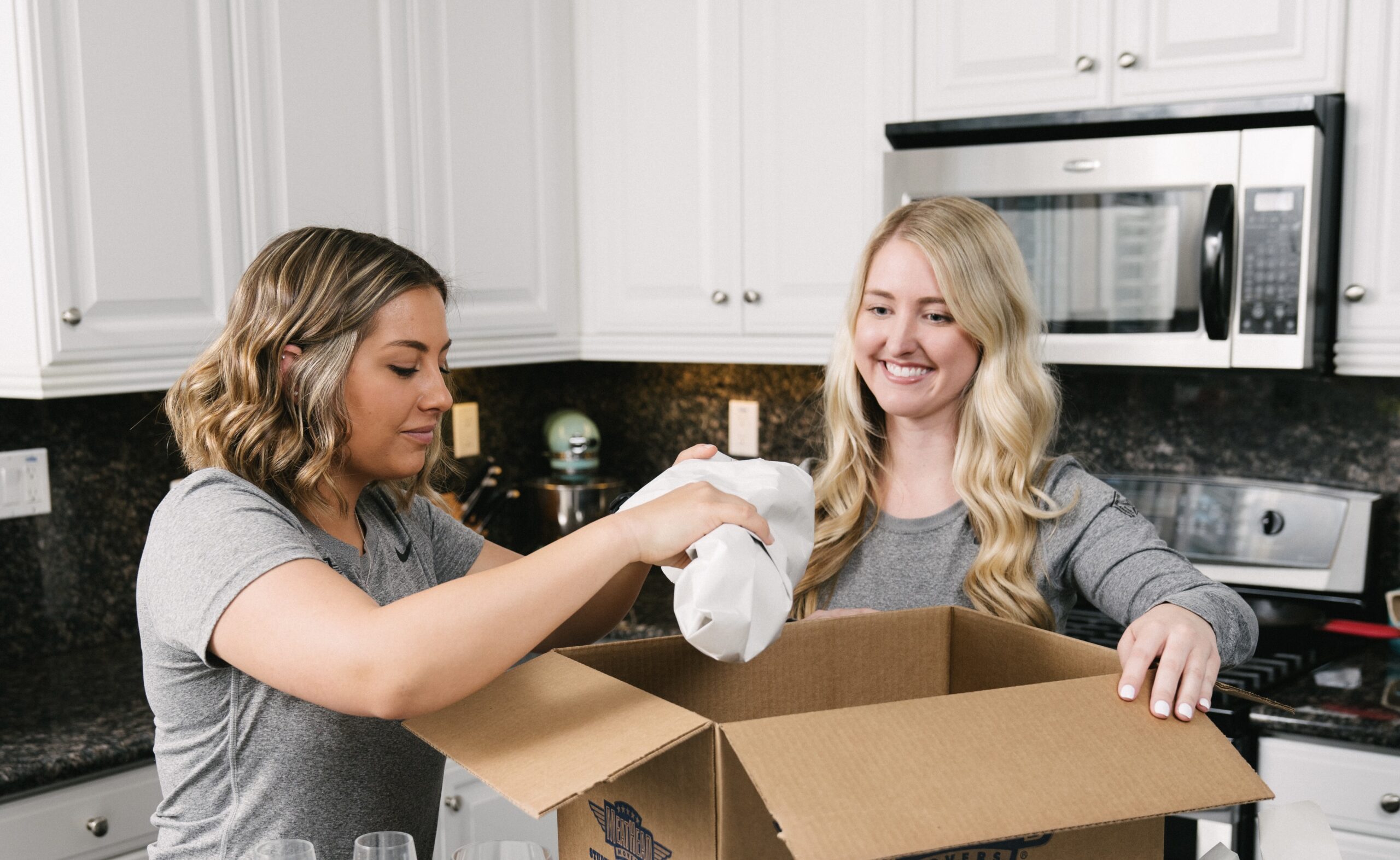 Two Meathead Packers placing a wrapped item in a moving box